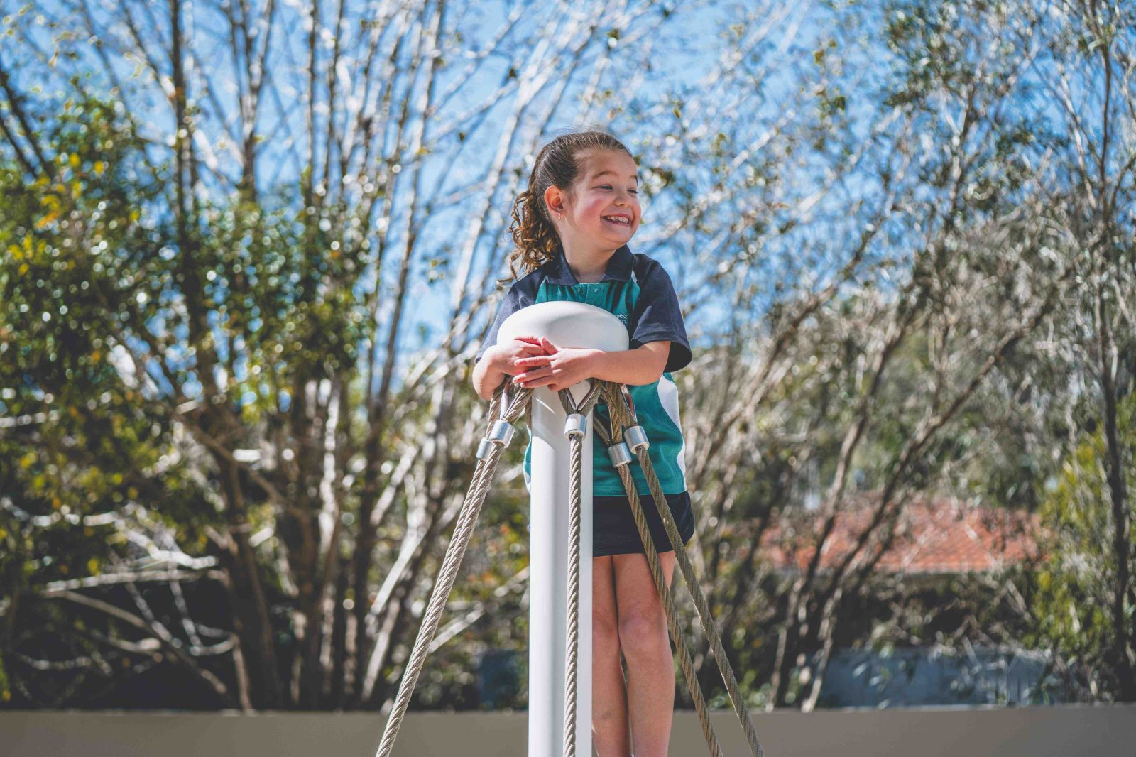 Smiling student plays outdoors on playground equipment
